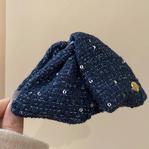 Close-up of navy blue tweed bow hair clip with silver sequins and gold believe medal