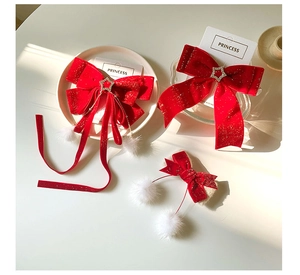 Detail of red velvet bow hair clip set with long streamers and white pom-poms