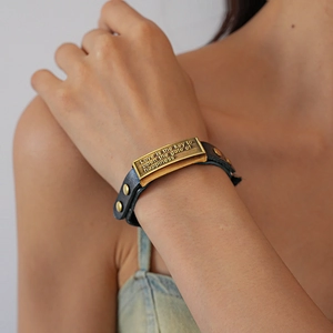 Detailed close-up of retro leather bracelet featuring an engraved bronze metal quote plaque