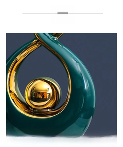 Close-up of modern ceramic art piece with emerald glaze and gold plated sphere details