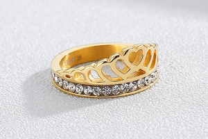 Macro detail of gold crown ring featuring hollow heart designs and sparkling rhinestones