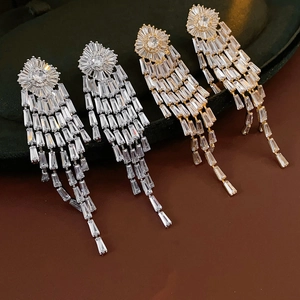 Detailed view of gold and silver tassel earrings with zircon stones on green velvet