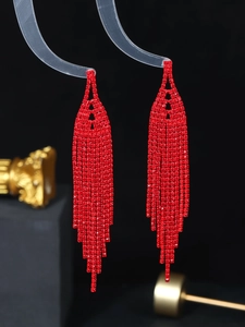 Macro detail of sparkling red rhinestone long tassel earrings with premium metal finish