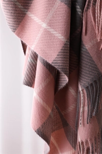 Close-up of pink, grey, and white plaid cashmere-like fabric with fringe details