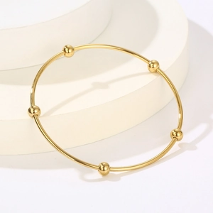 Minimalist gold stainless steel thin bangle featuring five polished round beads on white pedestal