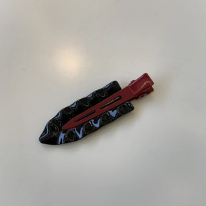 Detail of red and black seamless metal hair clip with glossy retro wave pattern