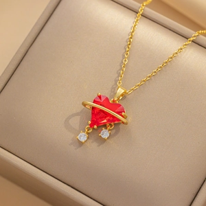 Detailed shot of golden heart necklace with red zircon in a beige jewelry gift box