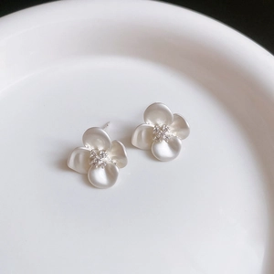 Macro shot of minimalist white flower stud earrings with zircon centers on ceramic