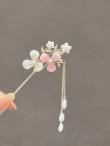 Detail of golden hairpin with pink magnolia flowers, pearls and flowing tassel chain