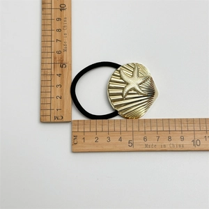 Detail of gold seashell and starfish metal hair tie with ruler measurements