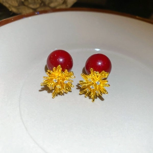 Macro shot of 18k gold-plated red resin stud earrings with zircon starburst details