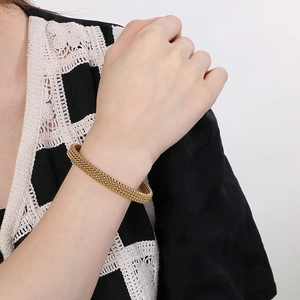 Close-up of golden stainless steel C-shaped woven bracelet on a female wrist
