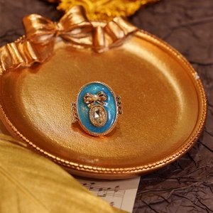 Vintage floral brooch with blue enamel crystal and gold bow tie on dark background