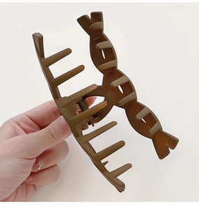 Detail view of large brown matte shark hair clip with strong spring in hand