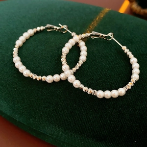 Detail of French vintage pearl hoop earrings with silver metal twist on green velvet