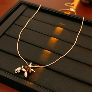 Detail of gold balloon dog pendant necklace featuring tiger eye bead on black tray