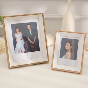 Modern light wood photo frames set with minimalist art on a clean home decor shelf