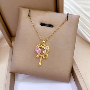Close-up of gold heart necklace with pink gemstone pendant in a champagne jewelry box