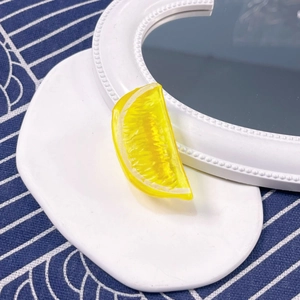 Detailed view of yellow resin lemon slice accessory on a white decorative display plate
