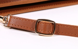 Detail of brown leather strap with polished gold metal buckle and smooth stitching