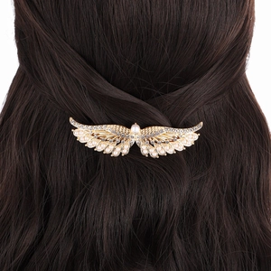 Detailed view of an angel wing hair clip with rhinestones and pearls on brown hair