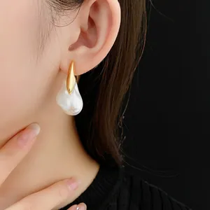 Baroque irregular pearl drop earrings with gold plating worn by model on black backdrop