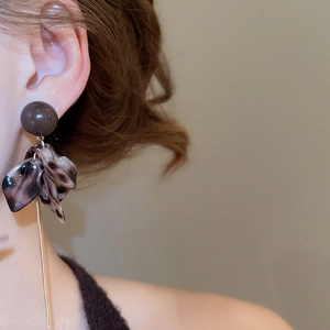 Gros plan détaillé de boucles d'oreilles rétro en résine léopard avec chaînes dorées chic