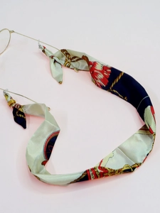 Detail of silk-like ribbon eyeglass chain with vintage floral pattern and metal clasp