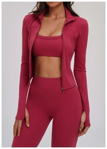 Detail der hochdehnbaren Fitnessjacke mit Daumenlöchern und Leggings in tiefem Magenta