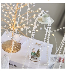 Close-up of elegant white pearl bead garland with a warm glowing LED pearl tree for XMAS decor