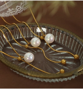 Nahaufnahme goldener Schlangenkette mit Perlen auf einem Vintage Glastablett