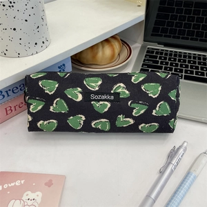 Floral pencil case with heart pattern on desk featuring stationery and laptop
