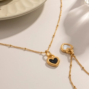 Detailed close-up of 18K gold heart necklaces with black and white textured pendants