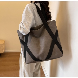 Detail view of the thick canvas tote bag with unique black crisscross wide strap design