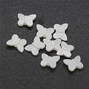 Macro detail of white faux pearl butterfly beads for DIY jewelry and hair accessories