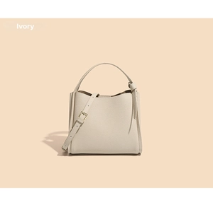 Detail view of ivory bucket bag showing lychee grain leather texture and knotted handle
