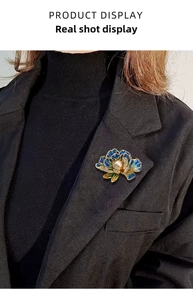 Detailed close-up of a blue enamel peony brooch with pearl on a black suit lapel