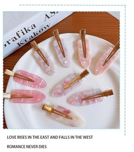 Flat lay of pink and white acetate hair clips with shell texture on a white plate