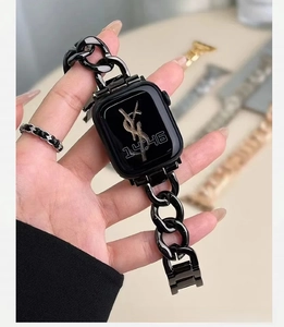 Detail view of glossy black metal chain strap on a smartwatch worn by a hand model