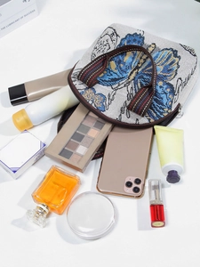 Ethnic style butterfly canvas handbag shown with daily essentials on white background