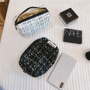 Detail of tweed makeup bags in black and white with a simple wish woven label