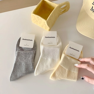 Three pairs of combed cotton ribbed ankle socks in cream colors with a paper tag