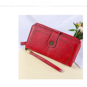 Dettaglio del portafoglio lungo in pelle rossa con bordo traforato e fibbia a girasole in bronzo