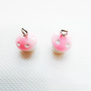 Detailed view of pink resin mushroom pendants with white dots and silver metal rings