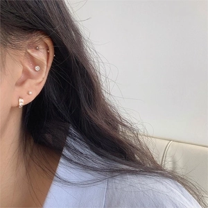 Close-up of minimalist square zircon hoop earrings and pearl studs on model ear