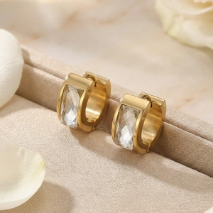Detail of golden huggie earrings with faceted clear crystal on champagne silk