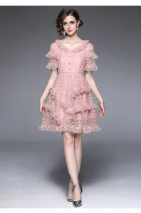 Detailed close-up of light pink lace dress with V-neckline and tiered ruffle layers