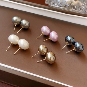 Flat high-luster pearl studs in gray, white, pink, gold and black on a brown display tray
