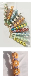 Close-up of handmade woven daisy charms with vibrant cotton textures and gold clips