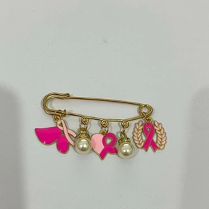 Détail des breloques ruban rose et perles sur une broche de sensibilisation au cancer du sein